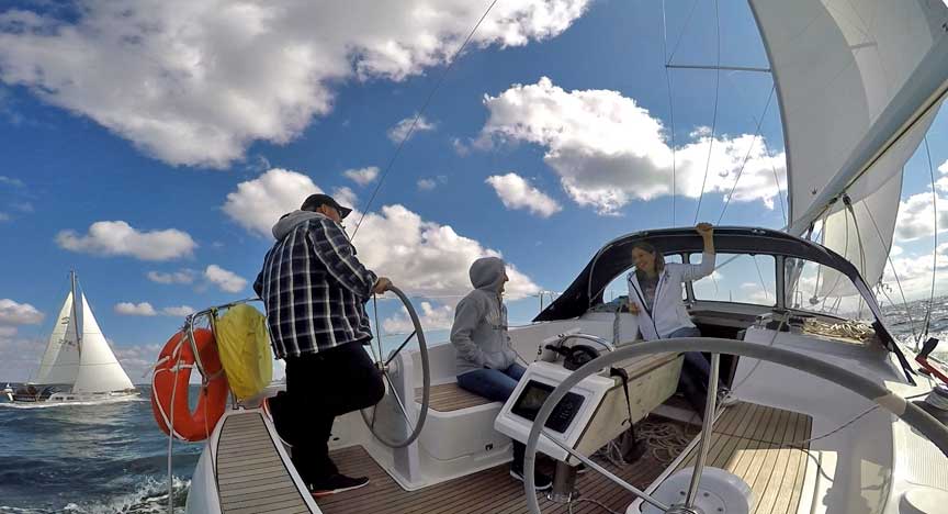 Segeln bei Sonne und Schäfchen-Wolken. Segel gesetzt und die Crew hat Spaß an Deck.