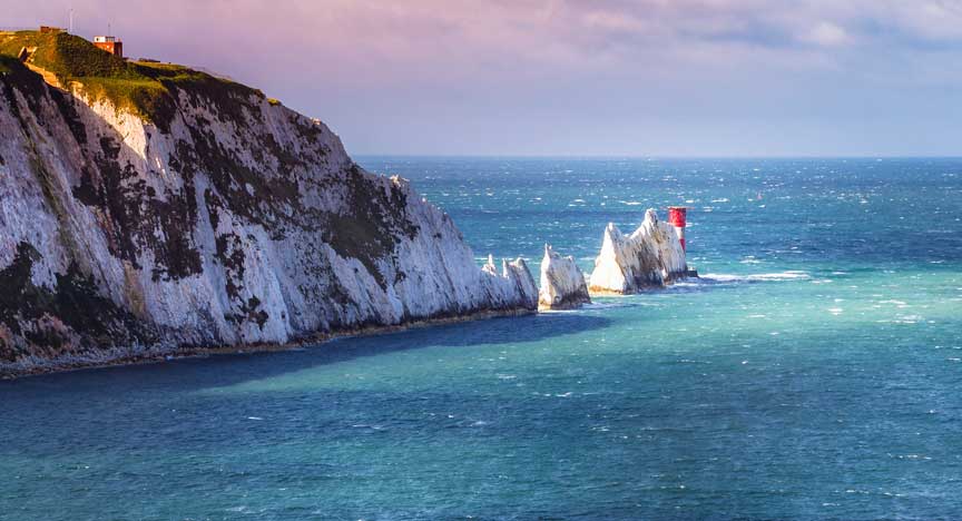 Eine Unterbrechung in den Wolken beleuchtet die ikonischen Kreidesteinspitzen von The Needles und den Leuchtturm aus dem 19. Jahrhundert auf der Küstenlinie der Isle of Wight, einer Insel vor der Südküste ...